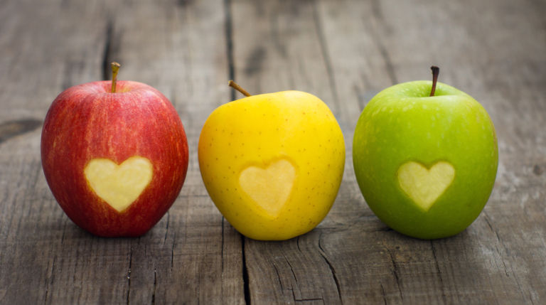 Three apples with engraved hearts on wood background